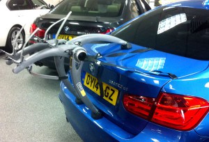 bmw 3 series in blue with a bike rack fitted in a bmw showroom