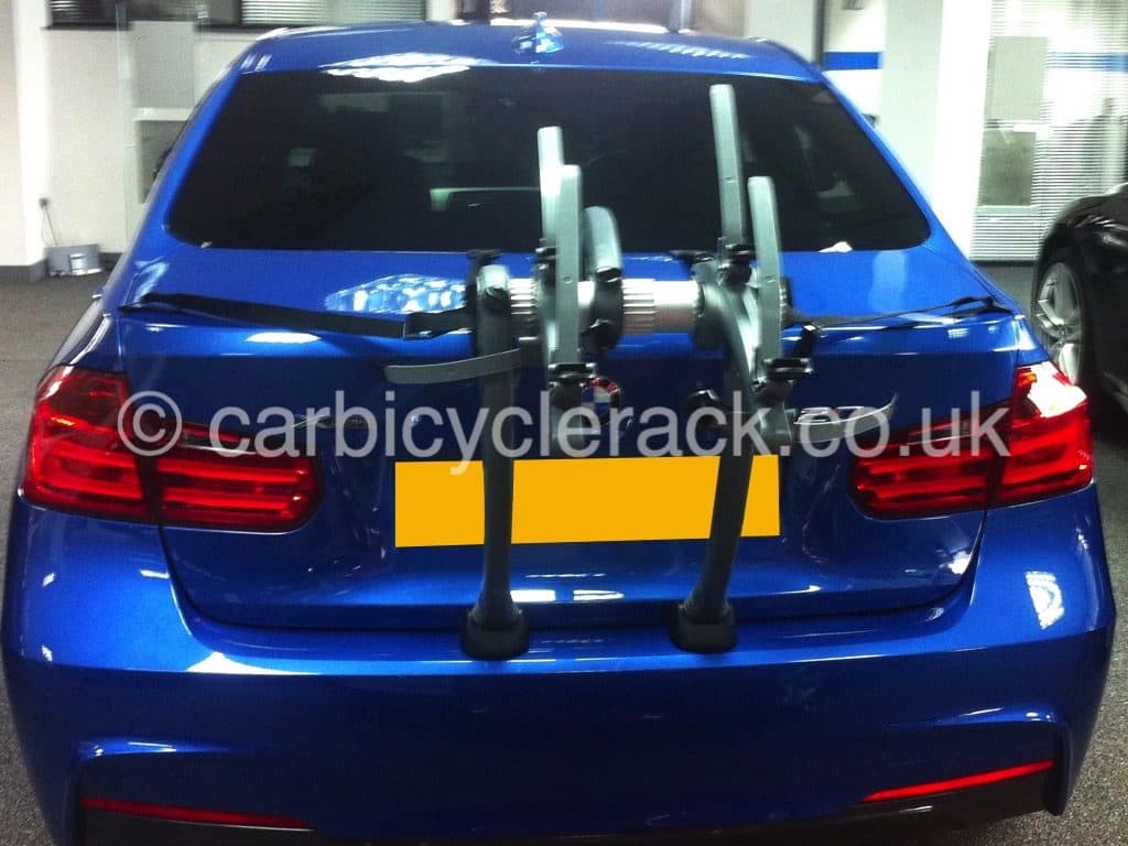 blue bmw 3 series saloon fitted with a bike rack in a bmw garage photographed from behind