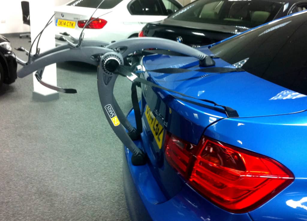 side view of a bmw 3 series saloon in blue with a bike rack fitted in a BMW garage